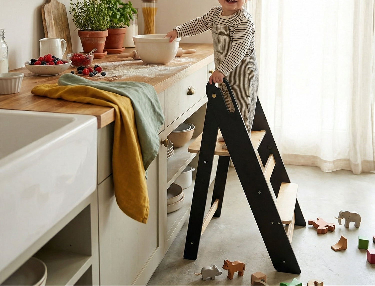 Child standing on a black step ladder in a kitchen